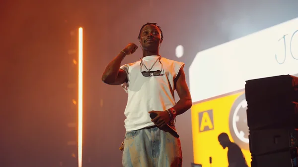 Asake performing onstage with a microphone at a 2024 Toronto concert.